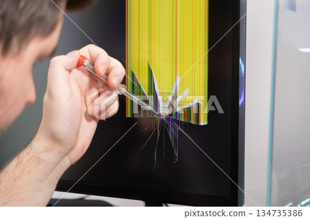 Skilled technician assessing a severely cracked computer monitor screen with a screwdriver, symbolizing urgent technology repair service and common hardware malfunction issues 134735386