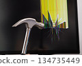 A hand holds a silver hammer smashing a black computer monitor screen, showing a crack with vibrant colorful lines, symbolizing technology failure, frustration, and digital overload 134735449