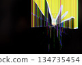 Broken display screen featuring prominent radial cracks and vibrant color pixel lines on a dark background, signifying technology damage, malfunction, and urgent repair 134735454