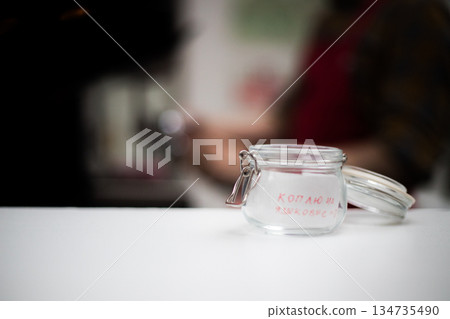 Tansparent cup for a tip with an inscription in a coffee house Tansparent cup for a tip with an inscription in a coffee house 134735490