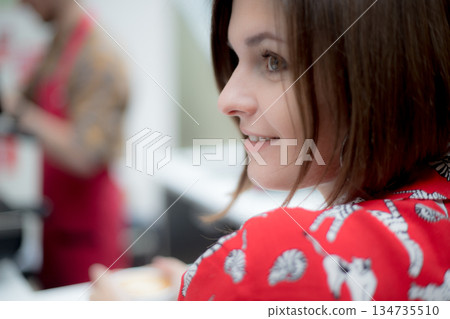 The young girl looks away and smiles against the background of the coffee house 134735510