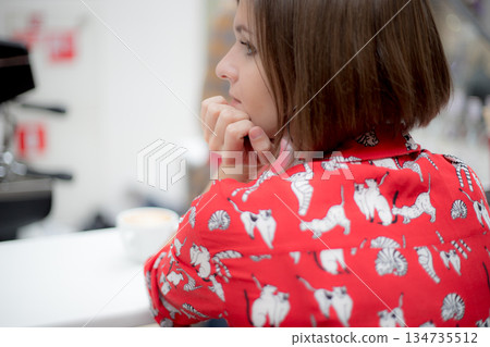 The young girl looks away in the background of a shopping cafe. Back view 134735512