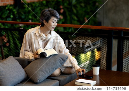 elder 50+ woman sitting  relax read book on sofa i 134735696