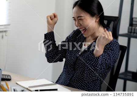 Smiling young businesswoman shows her delight and excitement 134735891