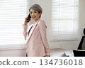 Smiling elder businesswoman stand talking on her mobile phone 134736018