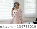 Smiling elder businesswoman stand talking on her mobile phone 134736019