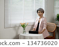 Senior businesswoman relaxing at desk in office while taking a break from work 134736020