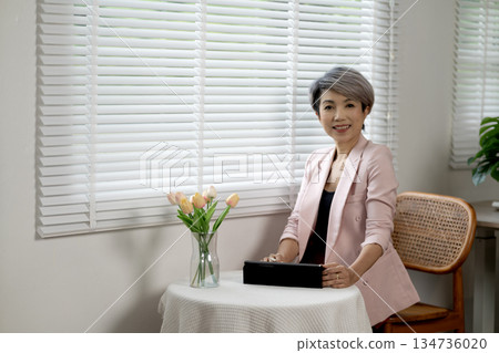 Senior businesswoman relaxing at desk in office while taking a break from work Senior businesswoman relaxing at desk in office while taking a break from work 134736020