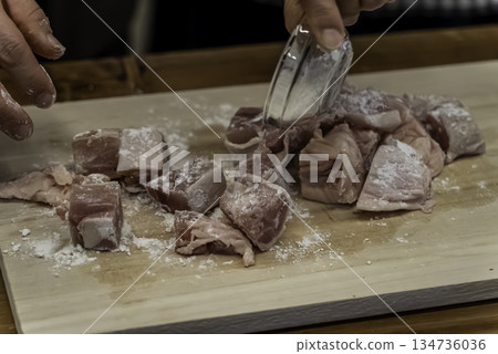Coat the chicken thighs in flour 134736036
