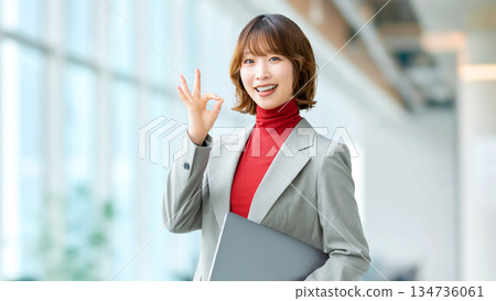 一位女性/女商人手持筆記型電腦,擺出「OK」的姿勢 一位女性/女商人手持筆記型電腦,擺出「OK」的姿勢 134736061