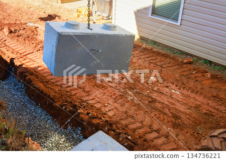 Concrete block is being lifted by crane at construction site while dirt to place at retaining walls Concrete block is being lifted by crane at construction site while dirt to place at retaining walls 134736221