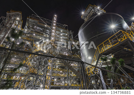 Night view of a huge factory. Night view of a shining biomass power plant and its plant equipment. Night view of a huge factory. Night view of a shining biomass power plant and its plant equipment. 134736881