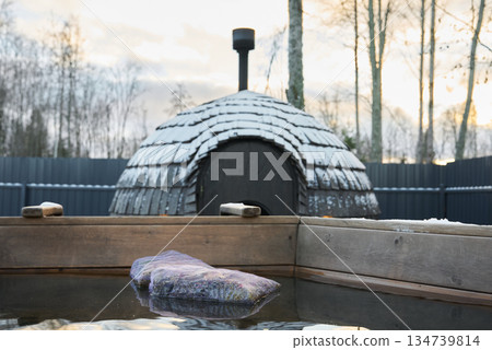 Tranquil winter landscape with steaming bath and artful cushions 134739814