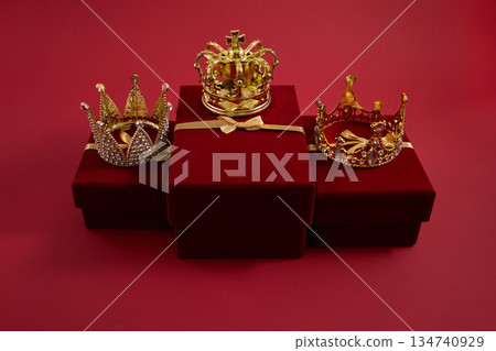 Three golden crowns on red velvet gift boxes. Three golden crowns representing Epiphany, three wise day 134740929