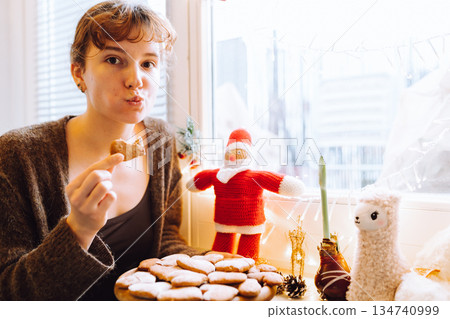 young woman holding gingerbread cookies on a wooden round board 134740999
