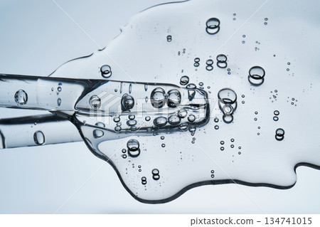 Clear cosmetic dropper with serum flowing, showing bubbles 134741015