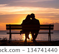 A couple cuddling on a bench against the sunset sky 134741440