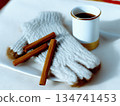 Warm gloves and cinnamon sticks next to a cup of coffee on a table 134741453
