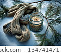 Warm candlelight and cozy scarf next to pine branches on a snowy surface 134741471