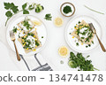 Fresh food served on two white plates with herbs and toppings in a bright setting 134741478