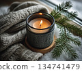 Cozy candle on a wooden stand with knit blanket and pine branch by a window in winter 134741479