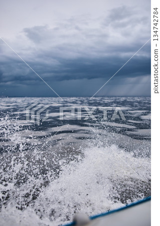splashing water from under the rubber boat in stormy weather, sailing regatta in the Gulf of Finland in heavily rain splashing water from under the rubber boat in stormy weather, sailing regatta in the Gulf of Finland in heavily rain 134742784