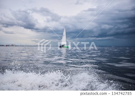 splashing water from under the rubber boat in stormy weather, sailing regatta in the Gulf of Finland in heavily rain splashing water from under the rubber boat in stormy weather, sailing regatta in the Gulf of Finland in heavily rain 134742785