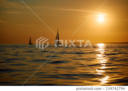 Sailing regatta in the Gulf of Finland at sunset, few sailing yachts competing in a race, splashing water from under the boats, teamwork, board the boat Sailing regatta in the Gulf of Finland at sunset, few sailing yachts competing in a race, splashing water from under the boats, teamwork, board the boat 134742794