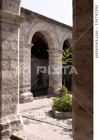A courtyard with a stone archway and a small garden 134742892