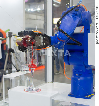 Robotic manipulators. Robot pouring liquid drink from bottle into glass. Industrial robot. Robot arm hand. Industrial manipulators for variety welding, material handling, palletizing. Robotization 134743043