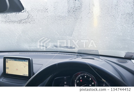 Inside the car, the windshield is being defrosted before departure. 134744452