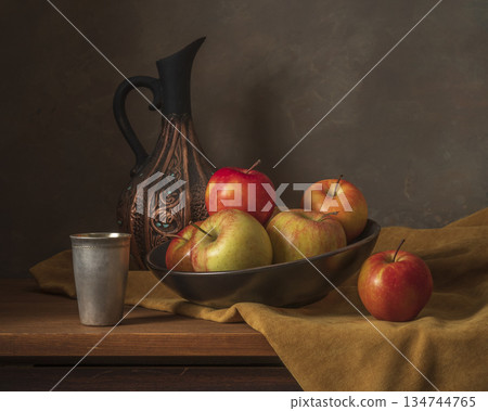 Still Life Of Apples In Bowl With Antique Jug And Metal Cup On Wooden Table 134744765