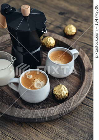 Black moka pot coffee maker with wooden handle and two cups of coffee Black moka pot coffee maker with wooden handle and two cups of coffee 134745606