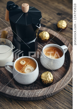 Black moka pot coffee maker with wooden handle and two cups of coffee Black moka pot coffee maker with wooden handle and two cups of coffee 134745610