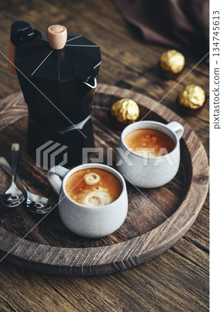 Black moka pot coffee maker with wooden handle and two cups of coffee Black moka pot coffee maker with wooden handle and two cups of coffee 134745613