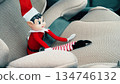 Close up of a festive Christmas elf doll placed on a modern car seat inside vehicle interior. Seasonal decoration concept combining holiday tradition family travel and everyday transportation 134746132