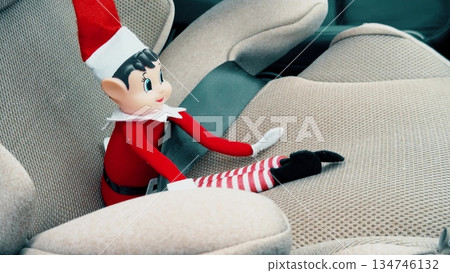 Close up of a festive Christmas elf doll placed on a modern car seat inside vehicle interior. Seasonal decoration concept combining holiday tradition family travel and everyday transportation Close up of a festive Christmas elf doll placed on a modern car seat inside vehicle interior. Seasonal decoration concept combining holiday tradition family travel and everyday transportation 134746132