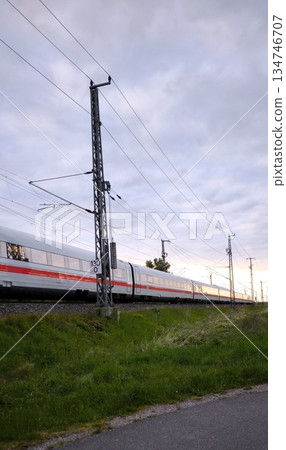 A high-speed ICE train rushes past a contact line support 134746707