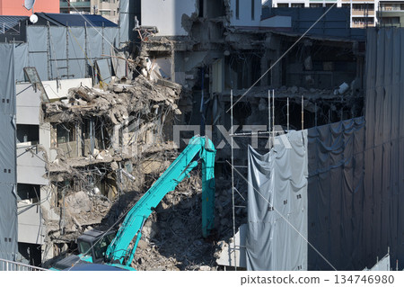 A dilapidated building being demolished. Demolition work using large heavy machinery. A dilapidated building being demolished. Demolition work using large heavy machinery. 134746980