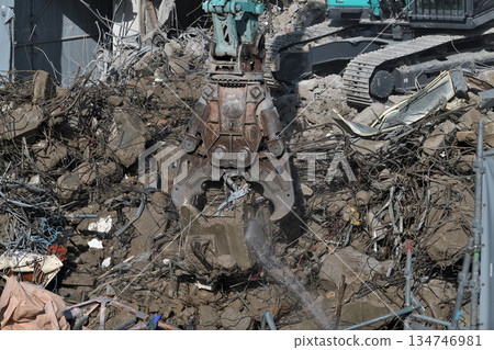 A dilapidated building being demolished. Demolition work using large heavy machinery. A dilapidated building being demolished. Demolition work using large heavy machinery. 134746981