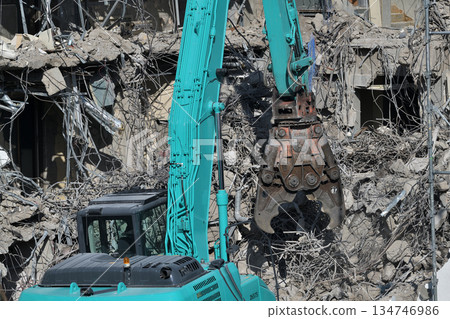 A dilapidated building being demolished. Demolition work using large heavy machinery. 134746986