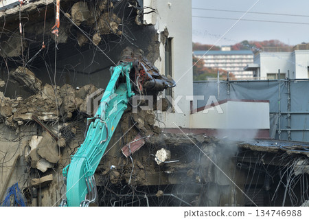 A dilapidated building being demolished. Demolition work using large heavy machinery. A dilapidated building being demolished. Demolition work using large heavy machinery. 134746988