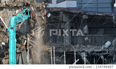 A dilapidated building being demolished. Demolition work using large heavy machinery. A dilapidated building being demolished. Demolition work using large heavy machinery. 134746997