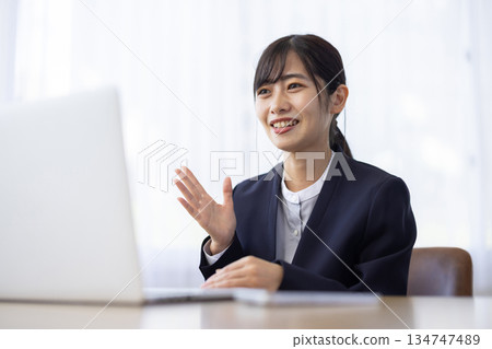 A woman in a suit smiling and having an online meeting A woman in a suit smiling and having an online meeting 134747489