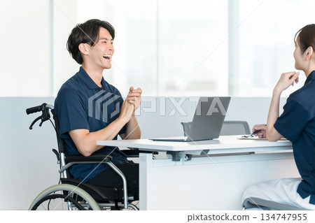 A male staff member in a wheelchair working at a desk in the office A male staff member in a wheelchair working at a desk in the office 134747955