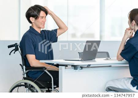A male staff member in a wheelchair working at a desk in the office A male staff member in a wheelchair working at a desk in the office 134747957