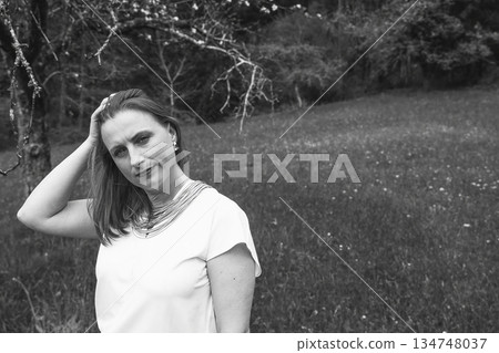 Happy middle-aged woman enjoying nature and embracing herself in spring field. Concept of self-love, female health, emotional balance, mindfulness, and positive aging Happy middle-aged woman enjoying nature and embracing herself in spring field. Concept of self-love, female health, emotional balance, mindfulness, and positive aging 134748037