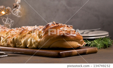 Braided Sweet Christmas Bread with Almonds and Icing Sugar on a Wooden Board 134749232