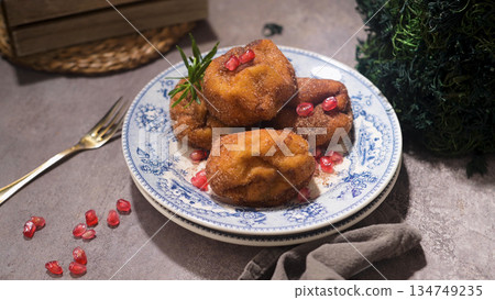 Gourmet Fried Fritters with Pomegranate Seeds and Rosemary on Vintage Blue Plate 134749235