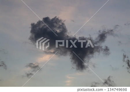 Dark cloud formation in blue sky at dusk creating dramatic atmosphere, perfect for weather forecasts and atmospheric backgrounds Dark cloud formation in blue sky at dusk creating dramatic atmosphere, perfect for weather forecasts and atmospheric backgrounds 134749698